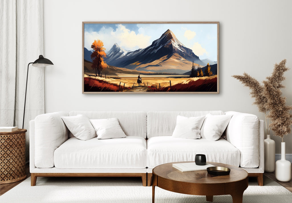 A large western mountain landscape art print featuring mountains and a cowboy on horse. 